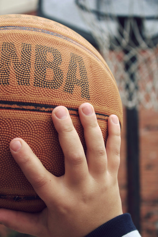 person holding brown basketball ball