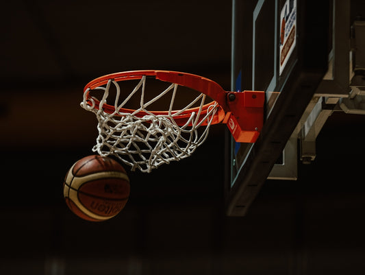 A basketball going through the hoop in a basketball court